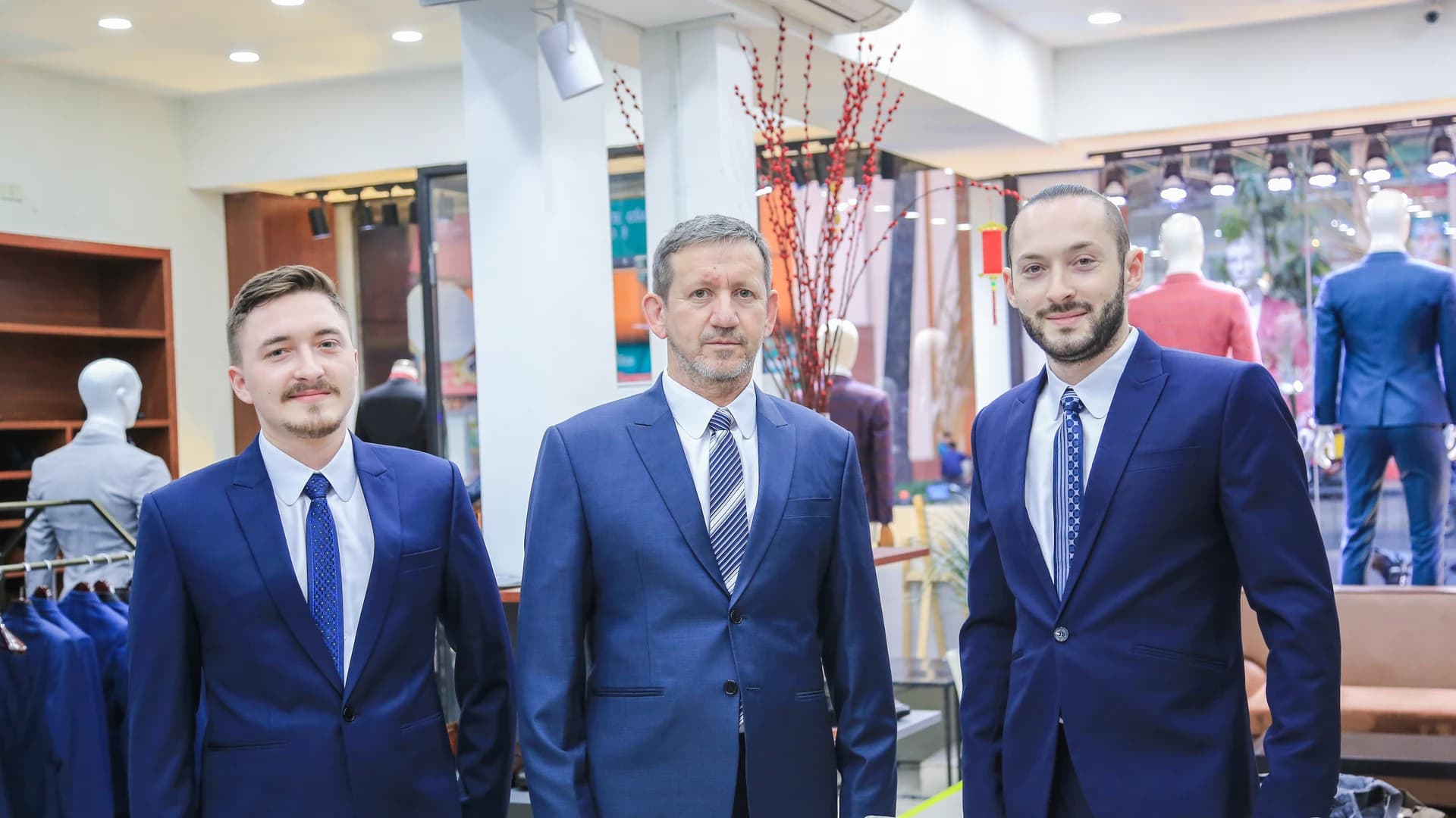 Ba khách hàng mặc vest xanh navy đồng bộ chụp tại showroom