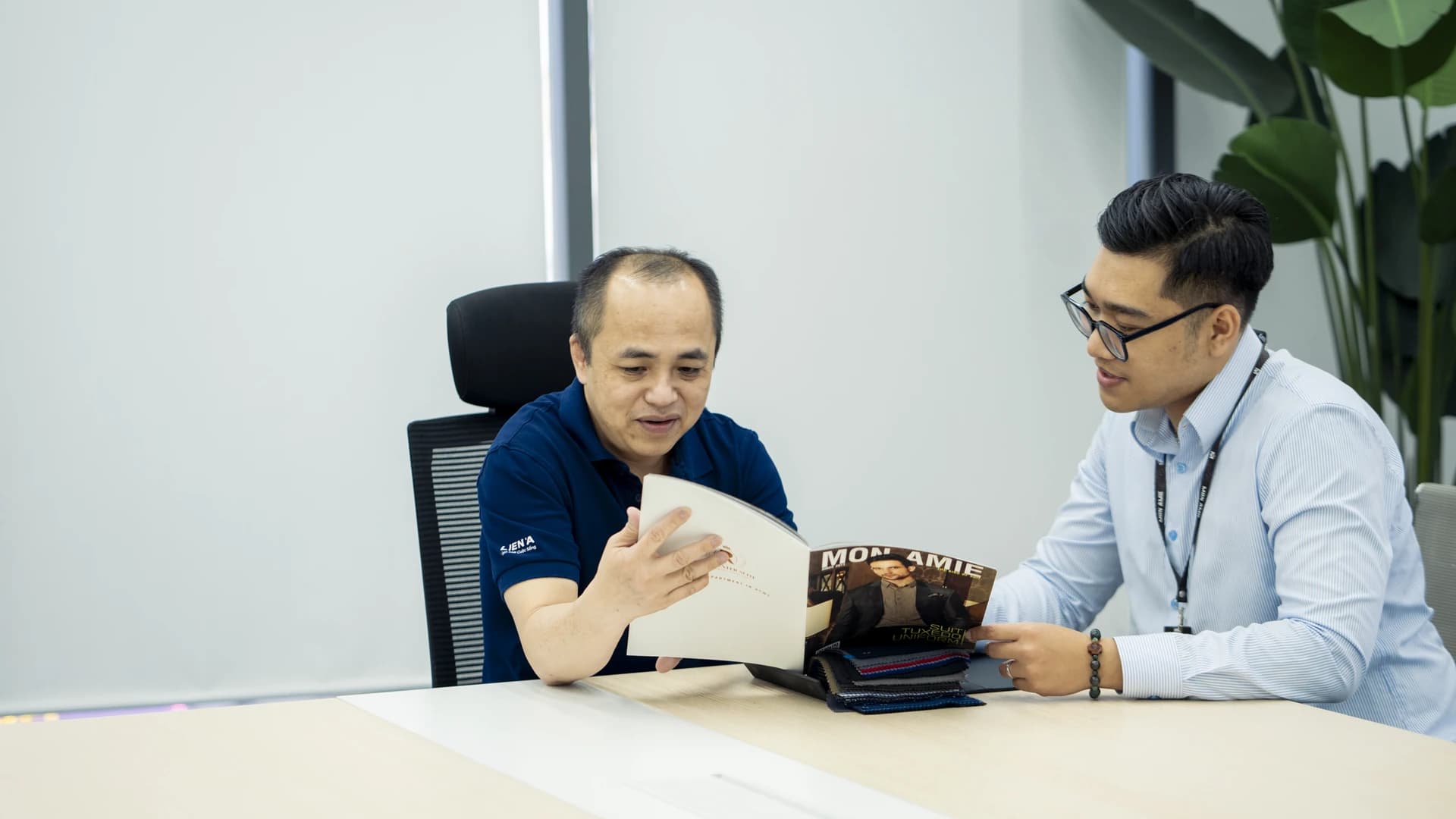 Nhân viên tư vấn giới thiệu sổ mẫu cho khách tại bàn làm việc