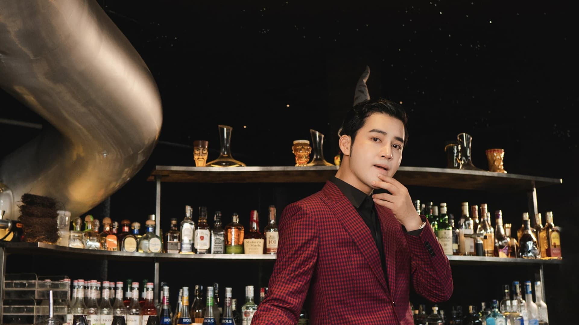 Người mẫu mặc vest đỏ đô thiết kế tại quầy bar tối kiểu dạ tiệc
