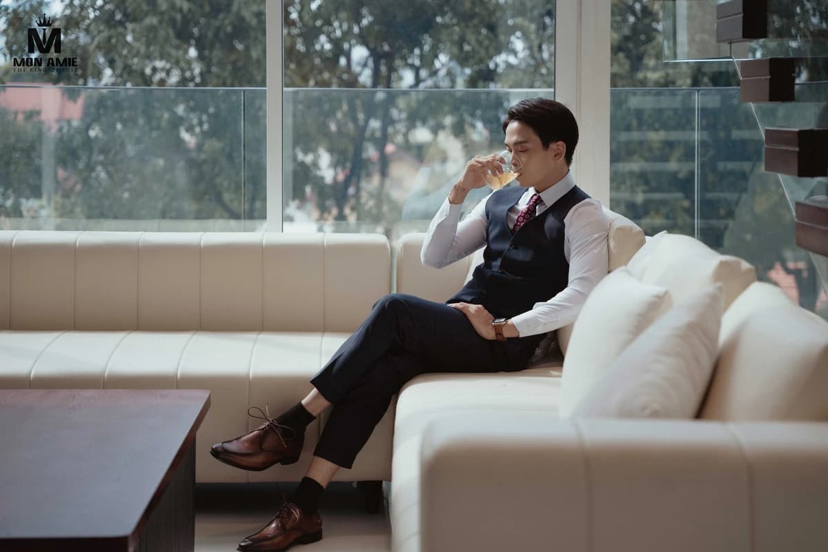 Doanh nhân mặc gile ngồi thư giãn trên sofa kem