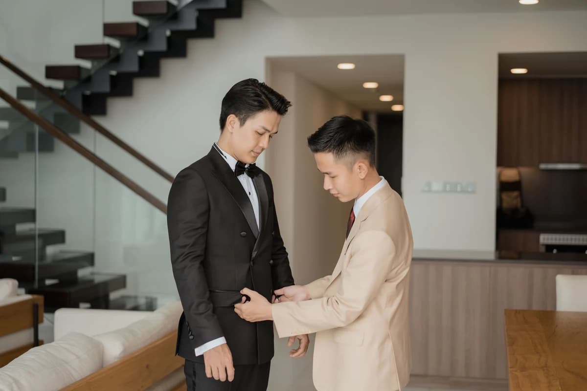 Thợ may chỉnh vest cho khách mặc tuxedo trong căn hộ