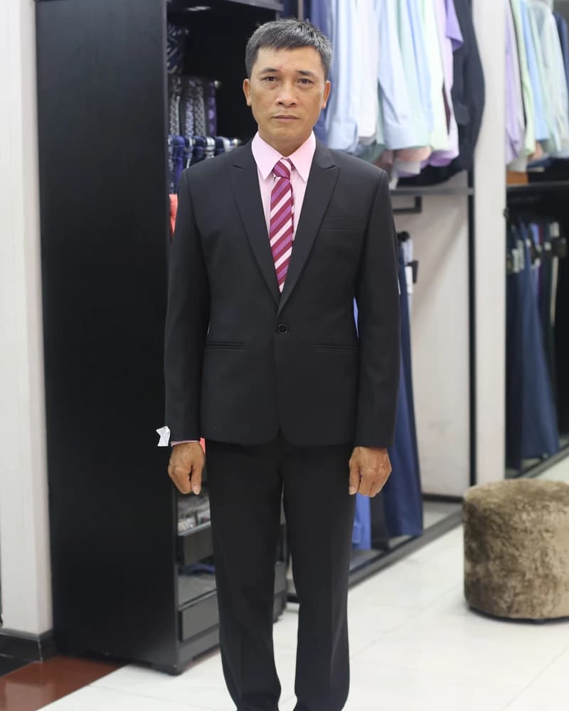 Quý ông mặc vest đen, cà vạt hồng sọc tại showroom